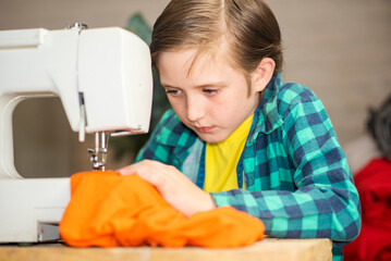 handsome boy sewing clothes on a sewing machine at home