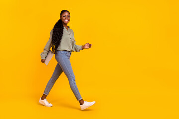 Fototapeta na wymiar Full body profile photo of cheerful charming lady walk empty space isolated on yellow color background