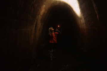 Female digger with flashlight explores the tunnel - 539024260