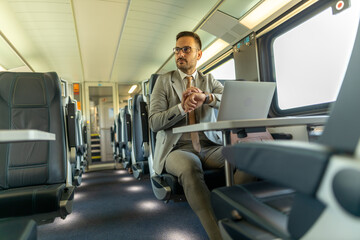 Fototapeta na wymiar Formal wearing business man traveling to work by train. Business man is working while traveling, using laptop, mobile phone, and taking notes. Business man planning goals and meetings