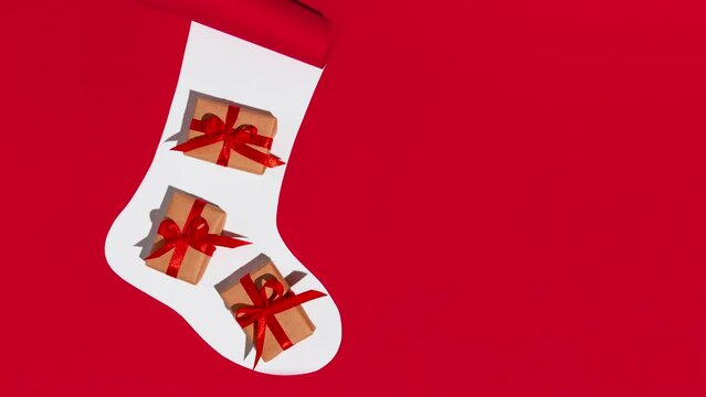 Christmas sock with gifts on white and red background. Stop motion animation. Space for text. Mockup.