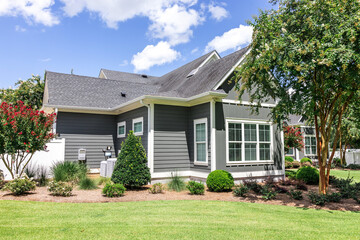 Side view of a large gray craftsman new construction house with a landscaped yard and a garage and driveway
