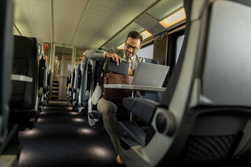 Formal wearing business man traveling to work by train.
Business man is working while traveling, using laptop, mobile phone, and taking notes.
Business man planning goals and meetings