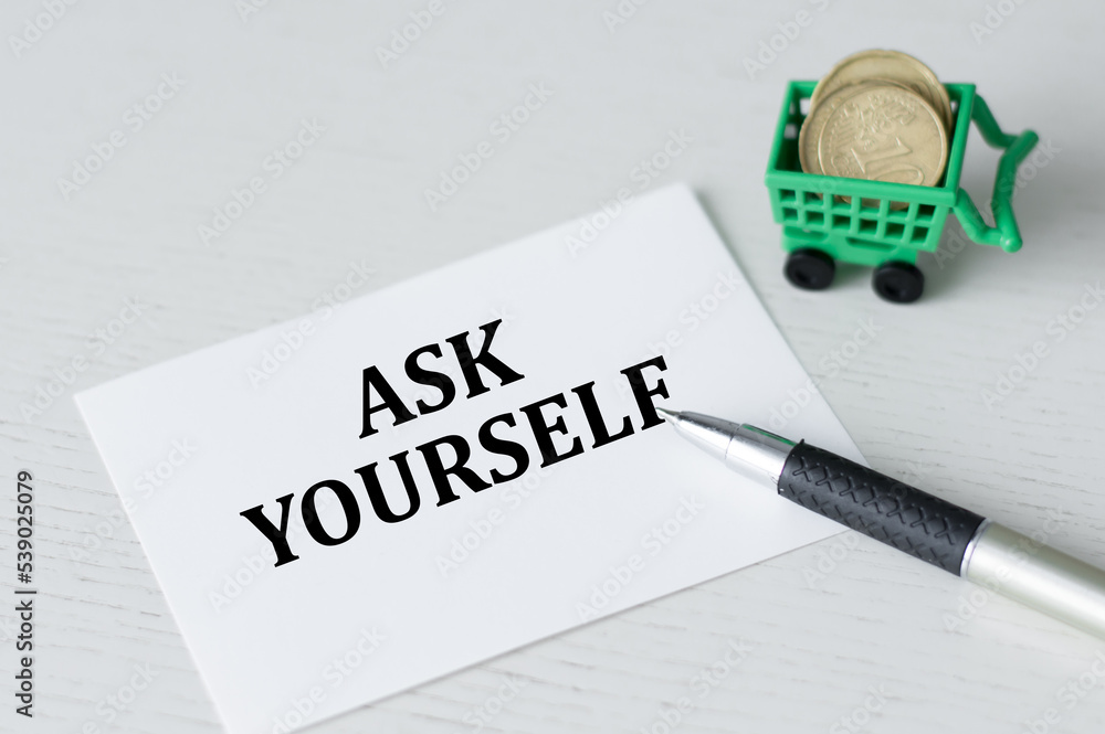 Poster ask yourself text on the card on the table next to the pen and coins