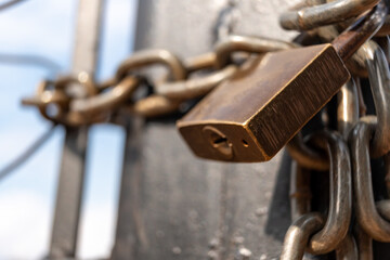 Metal chains and padlock locking a black gate with a blurred background