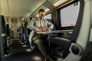 Fototapeta na wymiar Formal wearing business man traveling to work by train. Business man is working while traveling, using laptop, mobile phone, and taking notes. Business man planning goals and meetings