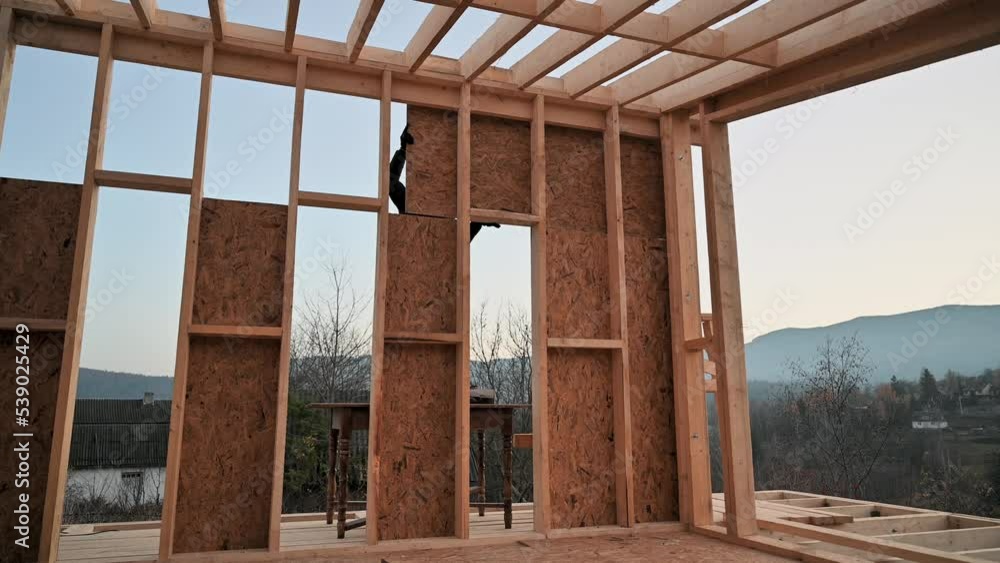 Canvas Prints Carpenters mounting wooden OSB panel on the wall of future cottage. Men workers building wooden frame house. Carpentry and construction concept.