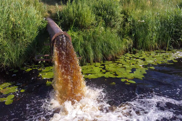 pollution enters the river. Dirty water flows from the pipe into the river.