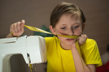  handsome boy sewing clothes on a sewing machine at home