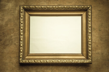Antique gold frame on a wooden background in vintage style. A picture frame with an empty middle for a photo.