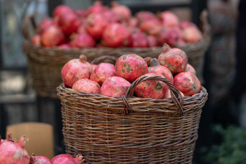 Harvest of ripe pomegranate in wicker baskets at outdoor farmers market in Tbilisi Georgia. Vegetarian healthy food
