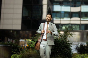 Business man holding laptop and mobile phone outdoors in front of his office
