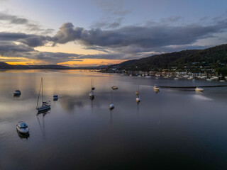Fototapeta premium Aerial sunrise waterscape with boats, rain clouds and reflections
