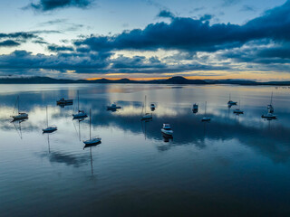 Aerial sunrise waterscape with boats, rain clouds and reflections