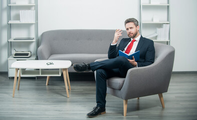mature businessman in suit sit in office taking notes in notebook