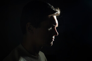 profile of thoughtful man looks to the right. portrait in side light, hard light, photo on black