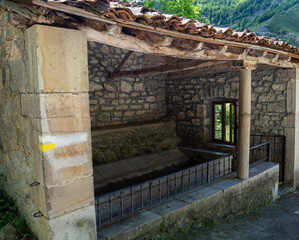 Lavadero antiguo de piedra con agua , una ventana y paredes de piedra, en verano de 2021, viajando por Asturias, España.