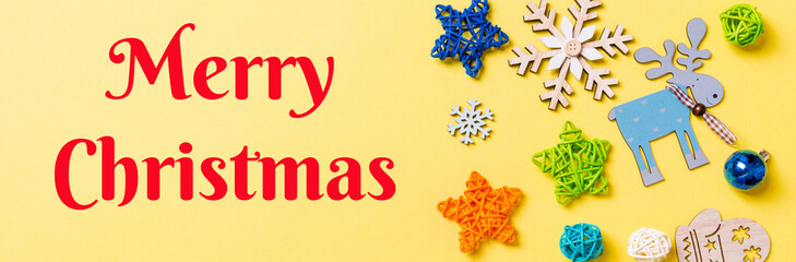 Merry Christmas text. Top view of yellow background with New Year toys and decorations. Christmas time Banner concept with copy space