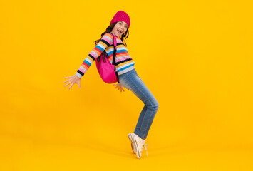 Fototapeta na wymiar Winter school. Teenager school girl with backpack in autumn clothes on yellow isolated studio background. Happy teenager, positive and smiling emotions of teen girl.