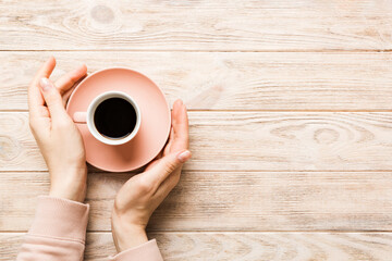 Fototapeta na wymiar Minimalistic style woman hand holding a cup of coffee on Colored background. Flat lay, top view cappuccino cup. Empty place for text, copy space. Coffee addiction. Top view, flat lay