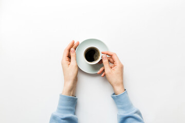 Minimalistic style woman hand holding a cup of coffee on Colored background. Flat lay, top view...