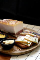 Fresh lard with meat layer on a wooden board with spices, mustard and horseradish. Delicious snack. Bacon.
