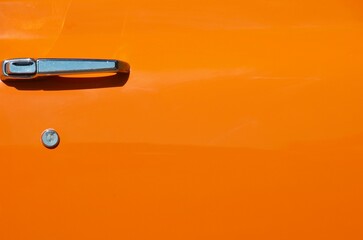 Bright orange surface with silver door handle copy space