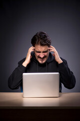 Young male hacker on grey background