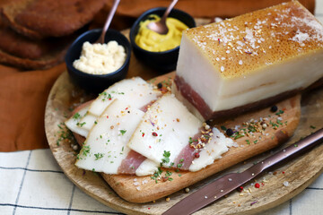 Fresh lard with meat layer on a wooden board with spices, mustard and horseradish. Delicious snack....