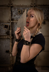 Fototapeta na wymiar Blonde woman holding piece of broken glass and licking . Dangerous risky act