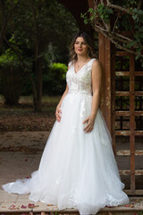 Naklejka premium Pregnant happy smiling bride with white wedding dress posing outdoor