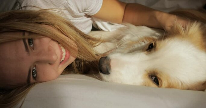 Close up very tender portrait of smiling young women huggin red dog puppy Border Collie in bed. white sheets and tshort. morning light, Prores
