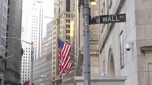 Wall St sign, USA flags and New York Stock Exchange background