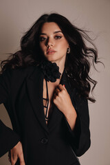 beautiful woman with dark hair in elegant black lingerie and jacket posing in studio