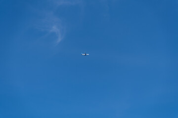 Low angle view of passenger airplane flying in clear blue sky with few cirrus clouds. Copy space for your text. Transportation theme.
