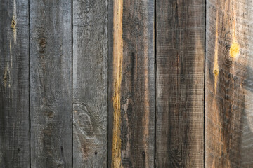 The texture of an old fence with a shadow. Wood texture with vertical lines. The texture of wood with knots and holes. The background of a fence damaged by time.