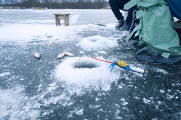 Winter fishing, ice fishing, ice hole and freshly caught fish lying on ice nearby