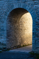 Light at the end of the tunnel - arch shaped passage in the old stone wall with copy space taken from an angle