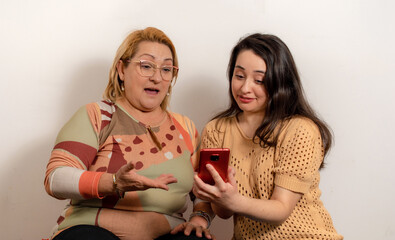 Hija enseñándole a su madre como usar una aplicación en su teléfono celular