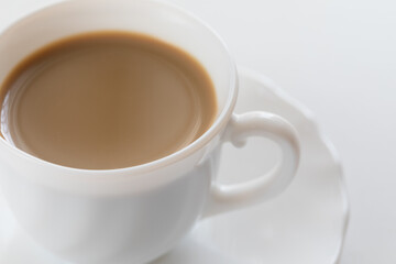 Tazza bianca con caffè e piattino su tavolo bianco