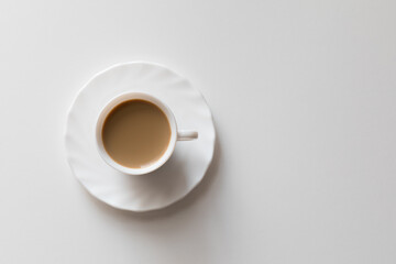 Tazza bianca con caffè e piattino su tavolo bianco