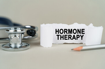 On a gray background, a stethoscope, a pencil and a paper plate with the inscription - HORMONE THERAPY