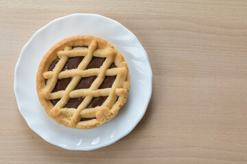 Crostata al cioccolato con piattino bianco su tavolo di legno