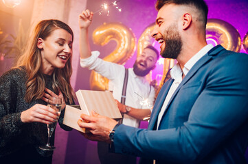 Couple exchanging gifts for birthday party or new years eve in the club