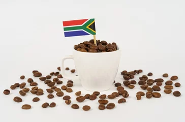 Crédence de cuisine en verre imprimé Bar a café The flag of South Africa sticks out of a cup of roasted coffee beans.