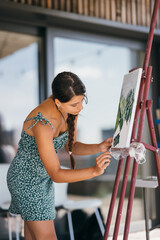 Young woman artist paints with a spatula on the canvas