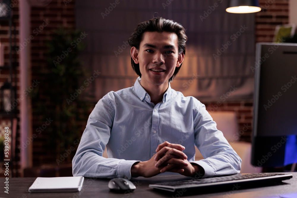 Poster portrait of asian man doing remote job at home, using computer to plan business report on online web