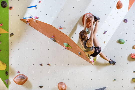Young woman bouldering in indoor climbing gym