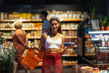 young woman do shopping in supermarket. choosing blueberry in store