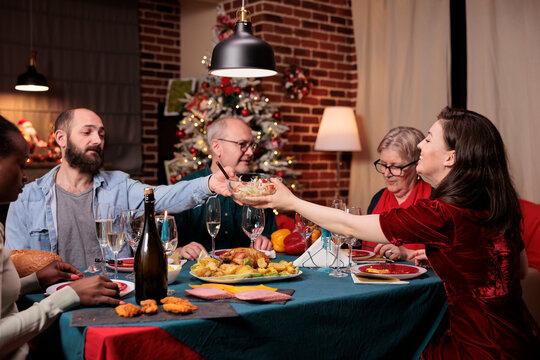 Big Diverse Family Having Christmas Dinner, Eating Traditional Food At Festive Table, Man Passing Woman Bowl With Dish. People Celebrating Xmas Holidays With Parents At Home Party